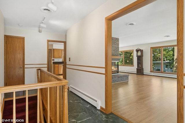 corridor with a baseboard radiator, an upstairs landing, visible vents, and track lighting