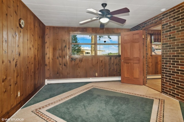 tiled spare room featuring wooden walls, a ceiling fan, and baseboard heating