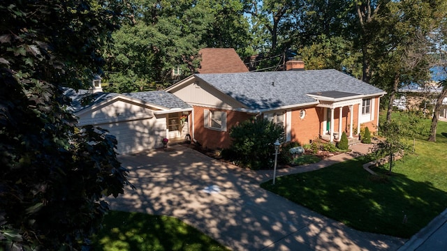 view of front of house with brick siding, concrete driveway, a front yard, roof with shingles, and a chimney
