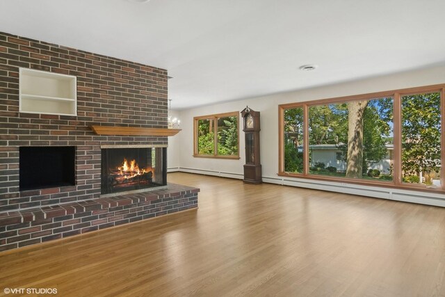 unfurnished living room featuring a brick fireplace, wood finished floors, a baseboard heating unit, and a baseboard radiator