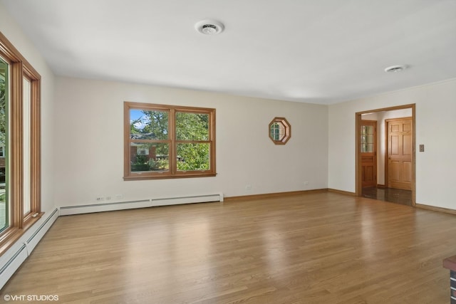 empty room featuring light wood-style floors, visible vents, baseboard heating, and baseboards