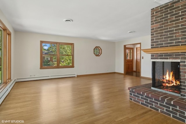 unfurnished living room with visible vents, a brick fireplace, baseboards, baseboard heating, and wood finished floors