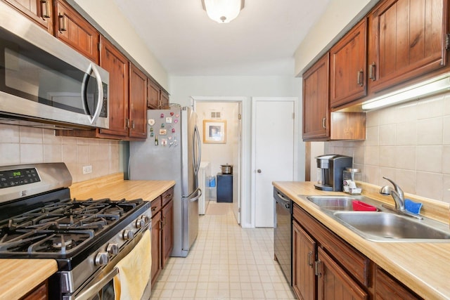 kitchen with backsplash, light floors, appliances with stainless steel finishes, and a sink