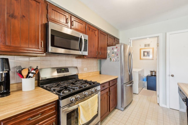kitchen featuring visible vents, backsplash, appliances with stainless steel finishes, light countertops, and washer / dryer