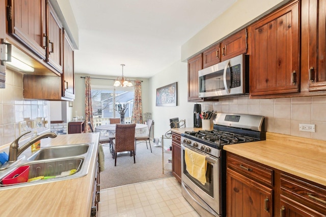 kitchen with light countertops, appliances with stainless steel finishes, hanging light fixtures, a notable chandelier, and a sink