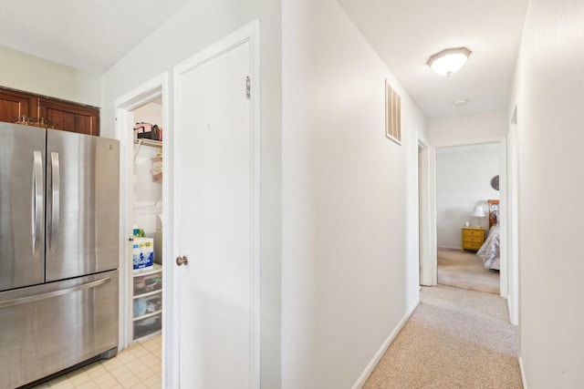 hall with baseboards, visible vents, and light carpet