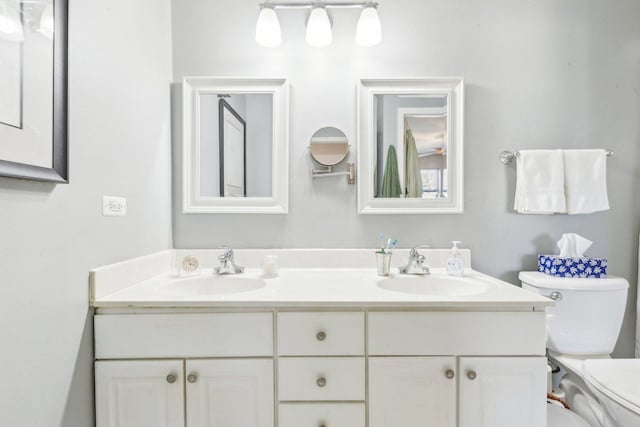 bathroom with a sink, toilet, and double vanity