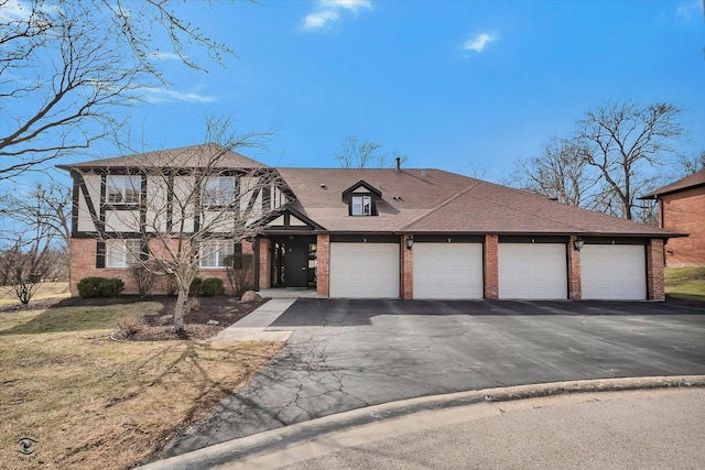 tudor house featuring roof with shingles and brick siding