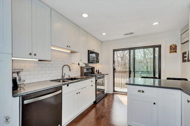 kitchen featuring tasteful backsplash, appliances with stainless steel finishes, a sink, visible vents, and dark wood-type flooring