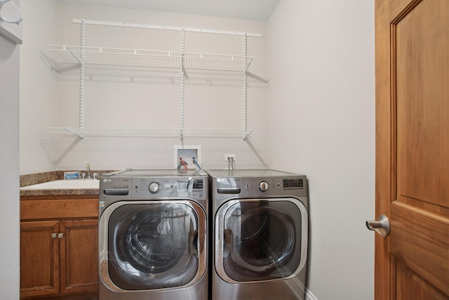 laundry area with cabinet space, independent washer and dryer, and a sink