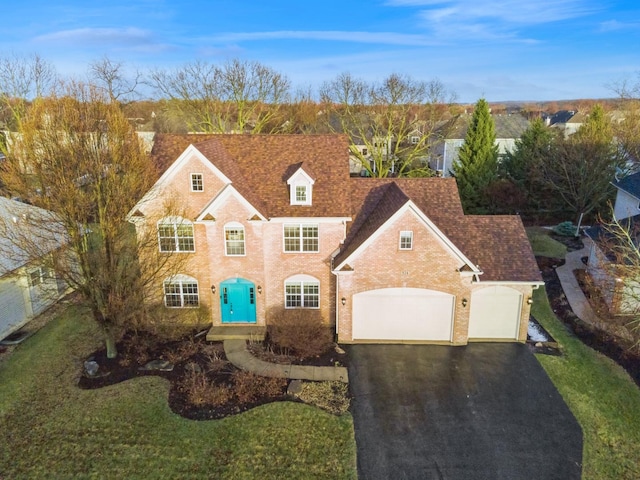 view of front of house featuring aphalt driveway, a front lawn, a garage, and a shingled roof