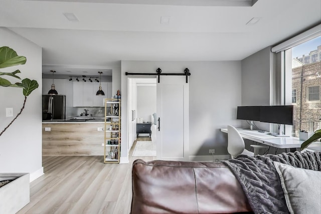 living room with baseboards, a barn door, and light wood-style flooring