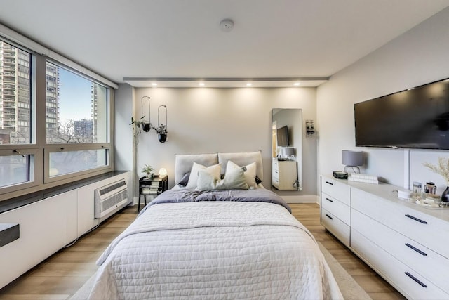 bedroom with an AC wall unit, light wood finished floors, and recessed lighting