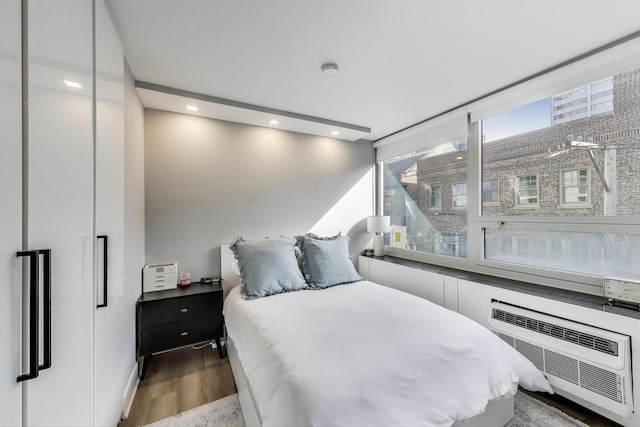 bedroom with a wall mounted AC, recessed lighting, and wood finished floors
