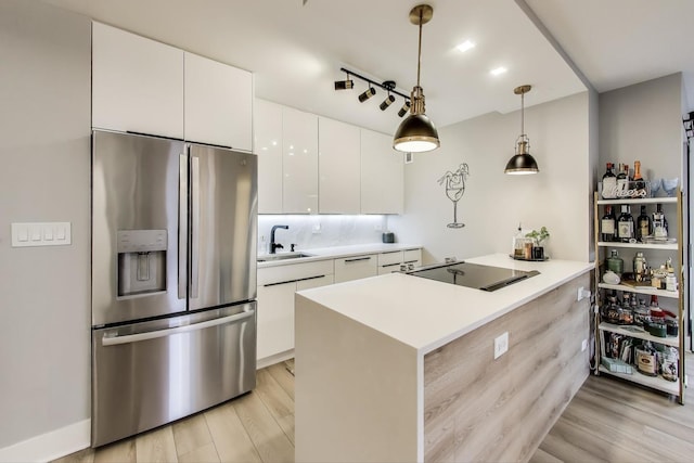 kitchen with a sink, stainless steel fridge, black electric cooktop, light wood-style flooring, and white cabinets
