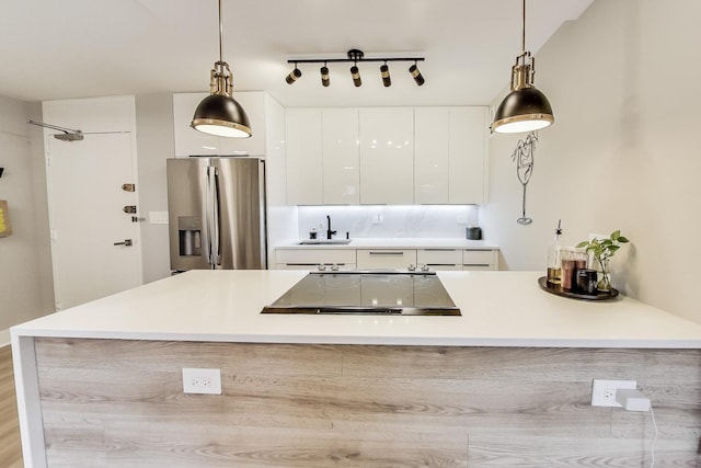 kitchen with white cabinetry, light countertops, stainless steel fridge with ice dispenser, a sink, and modern cabinets