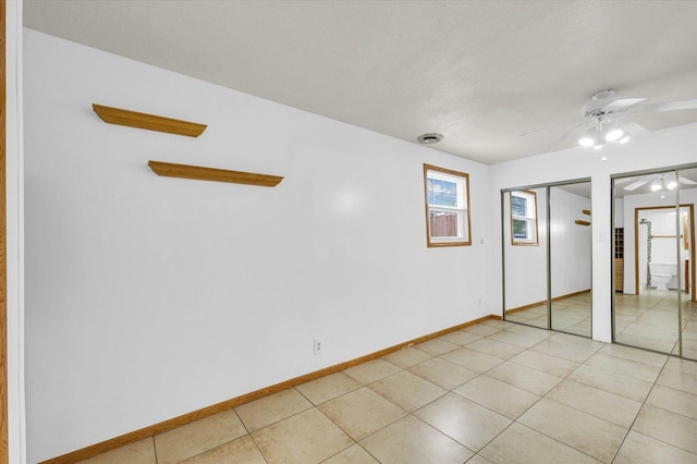 504 N 4th St, Saint Joseph, IL 61873 - unfurnished bedroom with multiple closets, baseboards, light tile patterned floors, a ceiling fan, and a textured ceiling