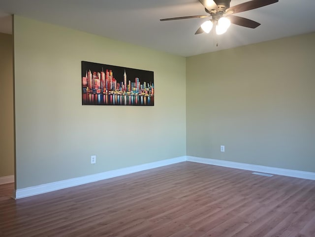 empty room with a ceiling fan, wood finished floors, and baseboards