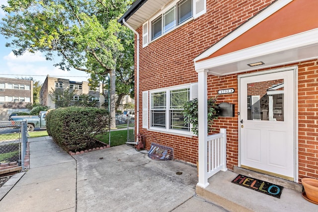 property entrance featuring brick siding and fence