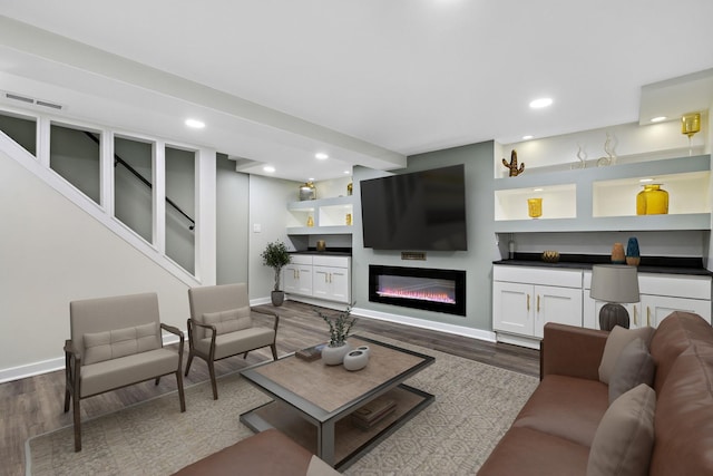 living area featuring recessed lighting, baseboards, a glass covered fireplace, and dark wood-type flooring