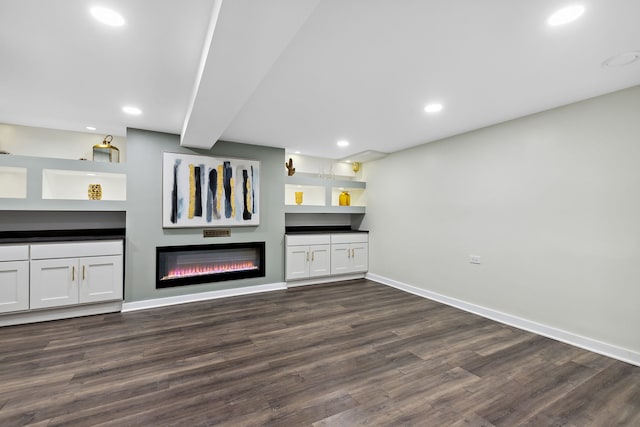 bar featuring a glass covered fireplace, baseboards, recessed lighting, and dark wood finished floors
