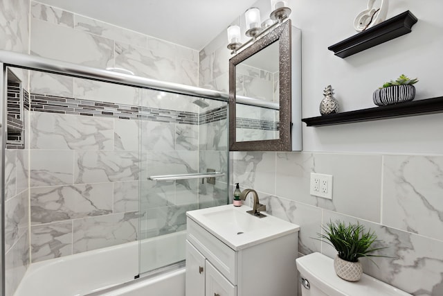 full bathroom featuring tile walls, vanity, toilet, and shower / bath combination with glass door