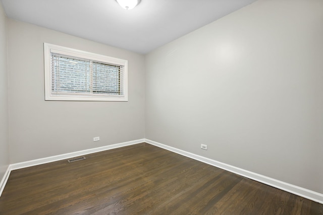 spare room featuring baseboards, visible vents, and dark wood-type flooring