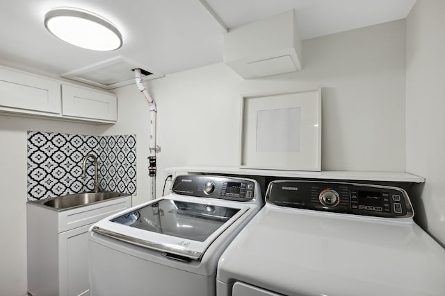 laundry area with cabinet space, separate washer and dryer, and a sink