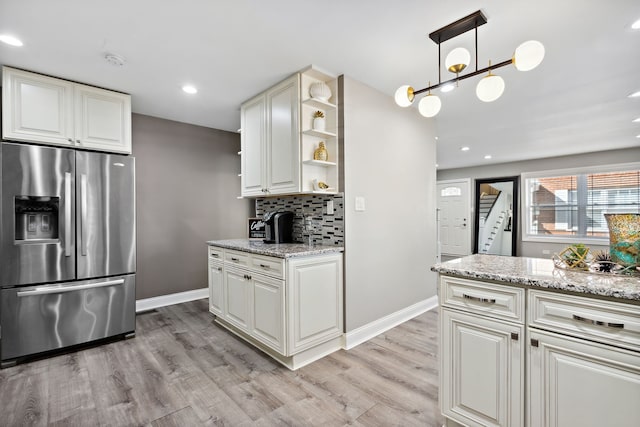 kitchen with backsplash, stainless steel refrigerator with ice dispenser, open shelves, baseboards, and light wood finished floors