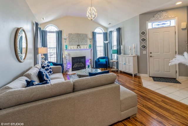 640 Schumann St, Woodstock, IL 60098 - living room featuring wood finished floors, lofted ceiling, a tile fireplace, a chandelier, and baseboards