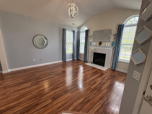 640 Schumann St, Woodstock, IL 60098 - unfurnished living room with healthy amount of natural light, wood finished floors, vaulted ceiling, a tiled fireplace, and baseboards