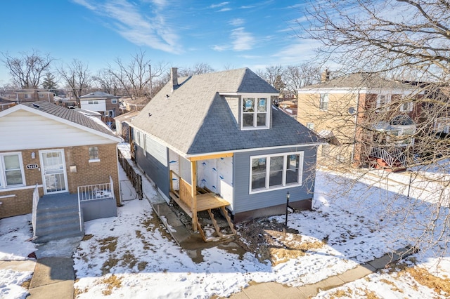 snow covered property with roof with shingles and a chimney