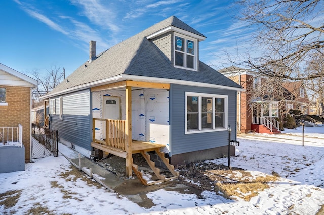 view of front of property with roof with shingles and fence