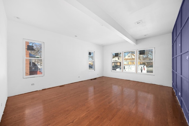 spare room featuring visible vents, beam ceiling, and wood finished floors