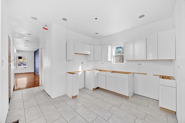 kitchen with a wealth of natural light, white cabinets, and light tile patterned floors