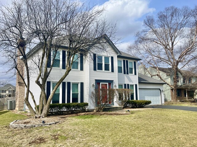 colonial home featuring an attached garage, driveway, and a front yard
