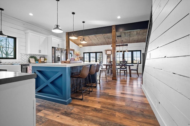bar area with stainless steel fridge, dark wood-style floors, pendant lighting, decorative backsplash, and recessed lighting