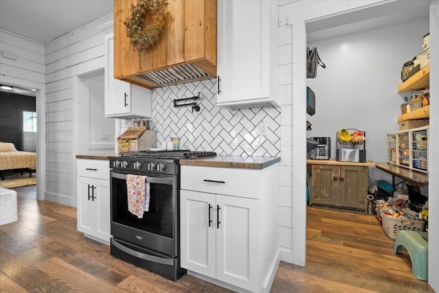 kitchen featuring stainless steel gas range, tasteful backsplash, dark countertops, and white cabinetry