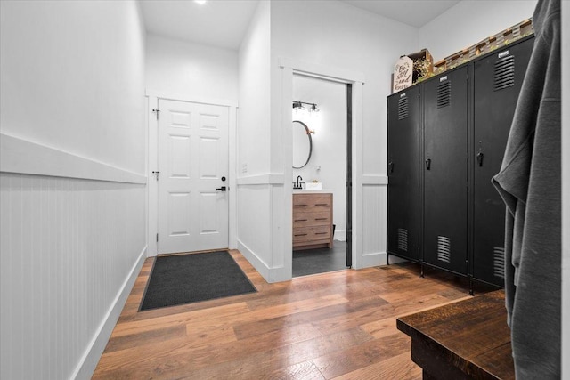 mudroom featuring wood finished floors, a sink, and baseboards