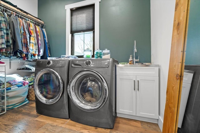 clothes washing area featuring cabinet space, independent washer and dryer, and wood finished floors