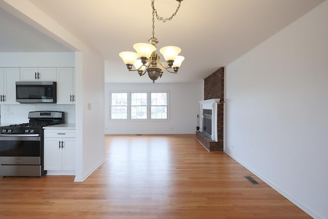kitchen with light wood finished floors, a notable chandelier, visible vents, and appliances with stainless steel finishes