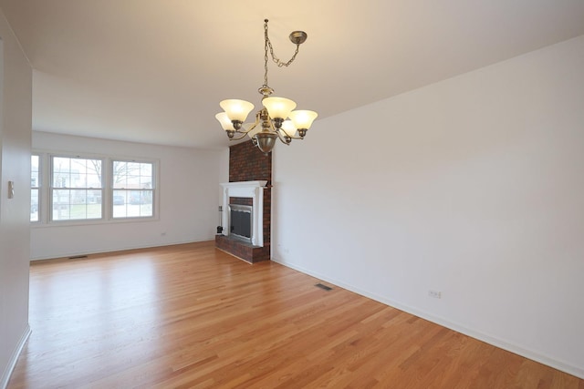 unfurnished living room featuring a chandelier, a fireplace, baseboards, and light wood-style flooring