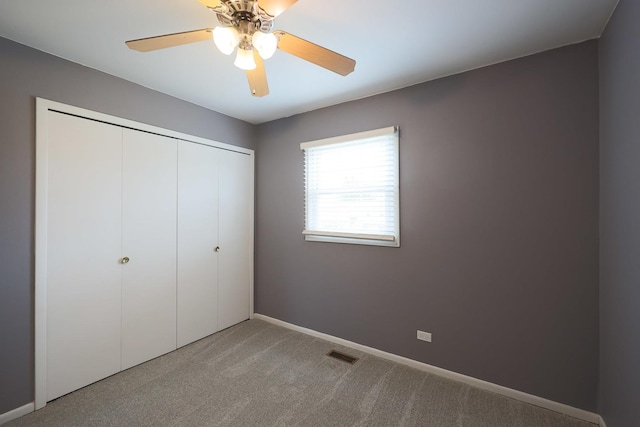 unfurnished bedroom with a closet, a ceiling fan, visible vents, carpet flooring, and baseboards