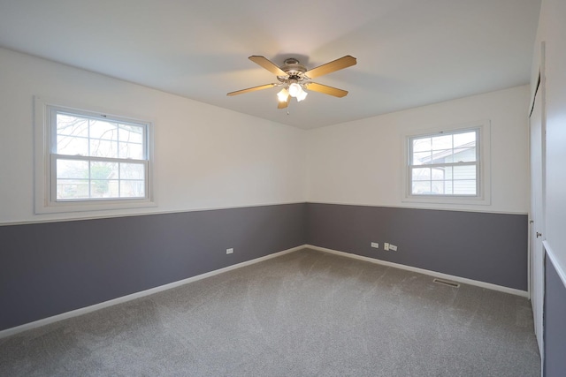 carpeted spare room with baseboards, a ceiling fan, and visible vents