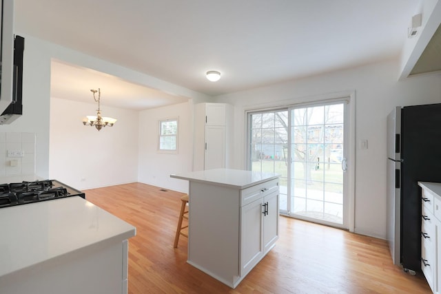 kitchen featuring light wood-style flooring, a chandelier, freestanding refrigerator, and white cabinets
