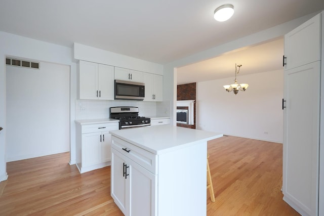 kitchen featuring visible vents, white cabinets, an inviting chandelier, stainless steel appliances, and decorative backsplash