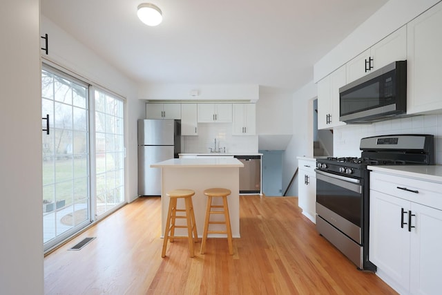 kitchen featuring backsplash, a kitchen island, visible vents, stainless steel appliances, and a sink