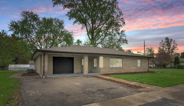 ranch-style home featuring a shingled roof, an attached garage, a front lawn, aphalt driveway, and central AC unit