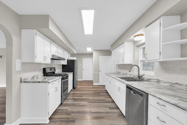 kitchen with open shelves, wood finished floors, under cabinet range hood, a sink, and stainless steel appliances