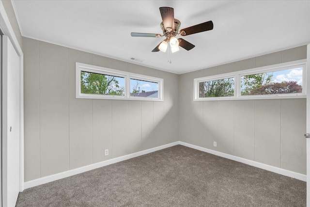 unfurnished bedroom with dark carpet, baseboards, ceiling fan, and visible vents